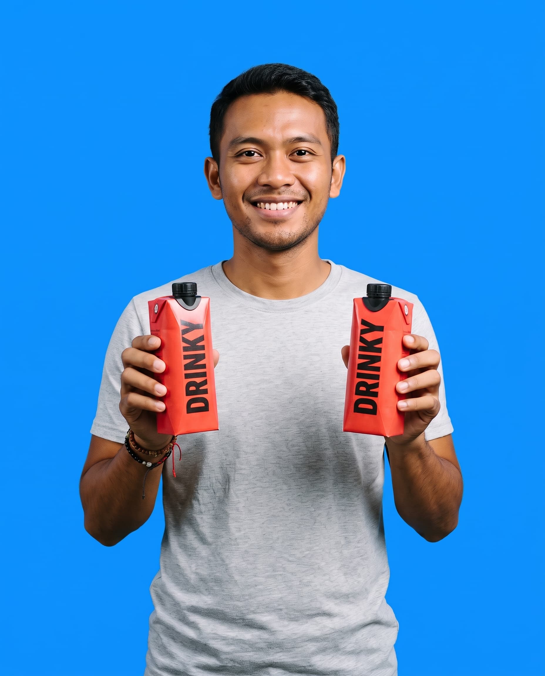 A smiling young man holding up two red DRINKY cartons
